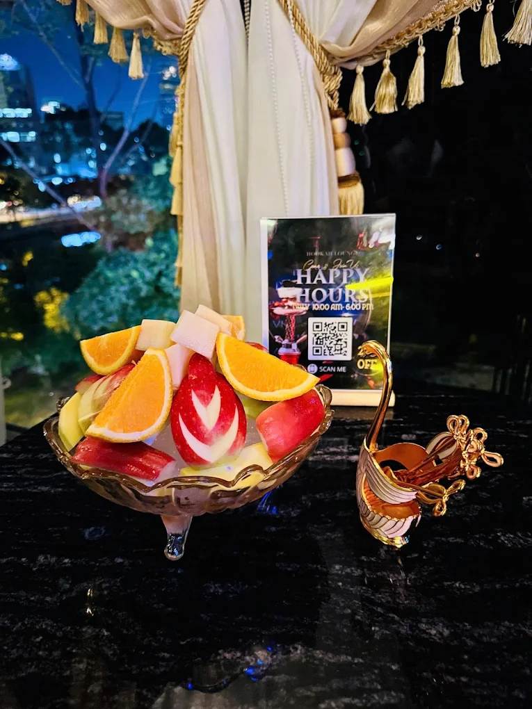 Fresh fruit platter with Happy Hours sign and city night view