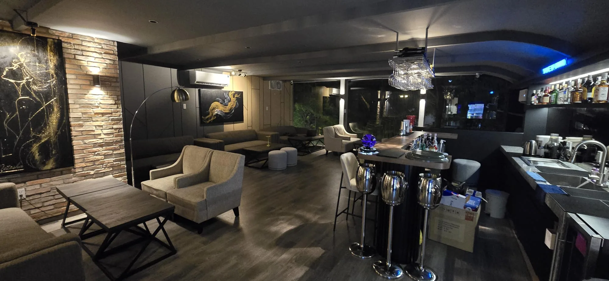 Natasha Noir Lounge interior with armchairs, brick wall art and bar counter